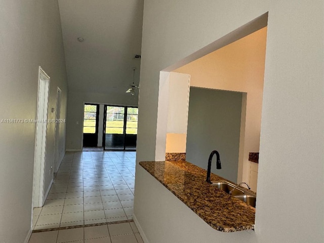 corridor with sink, a towering ceiling, and light tile patterned flooring