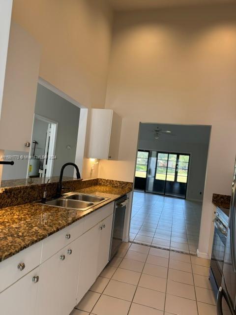 6114 SE Georgetown Pl, Hobe Sound, FL 33455 - kitchen featuring stainless steel dishwasher, light tile patterned floors, a high ceiling, a sink, and black electric range oven