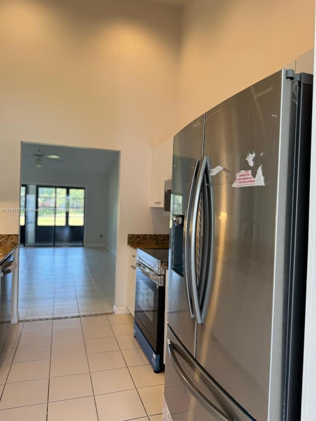 kitchen featuring range with electric cooktop, light tile patterned floors, and stainless steel refrigerator with ice dispenser