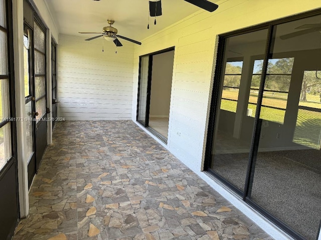 unfurnished sunroom with ceiling fan