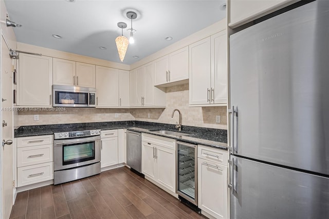 kitchen with sink, wine cooler, hanging light fixtures, appliances with stainless steel finishes, and dark hardwood / wood-style flooring