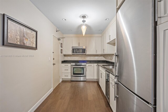 kitchen featuring sink, dark hardwood / wood-style floors, backsplash, white cabinets, and appliances with stainless steel finishes