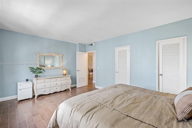 bedroom with hardwood / wood-style floors and multiple closets