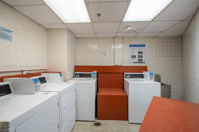 washroom featuring separate washer and dryer, light tile patterned floors, and tile walls