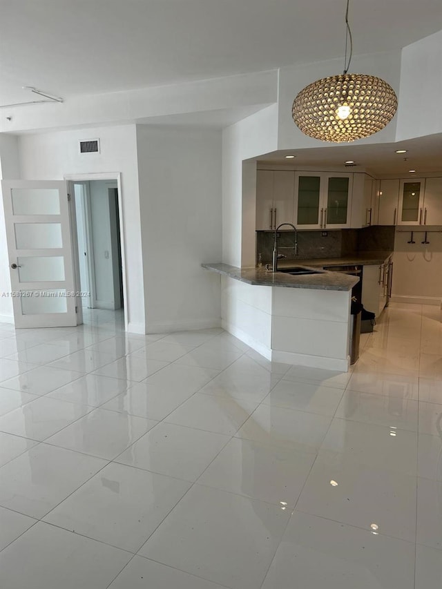 kitchen with sink, kitchen peninsula, backsplash, and light tile floors