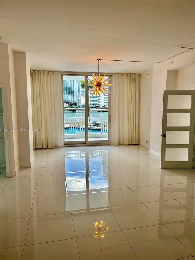 tiled spare room with an inviting chandelier