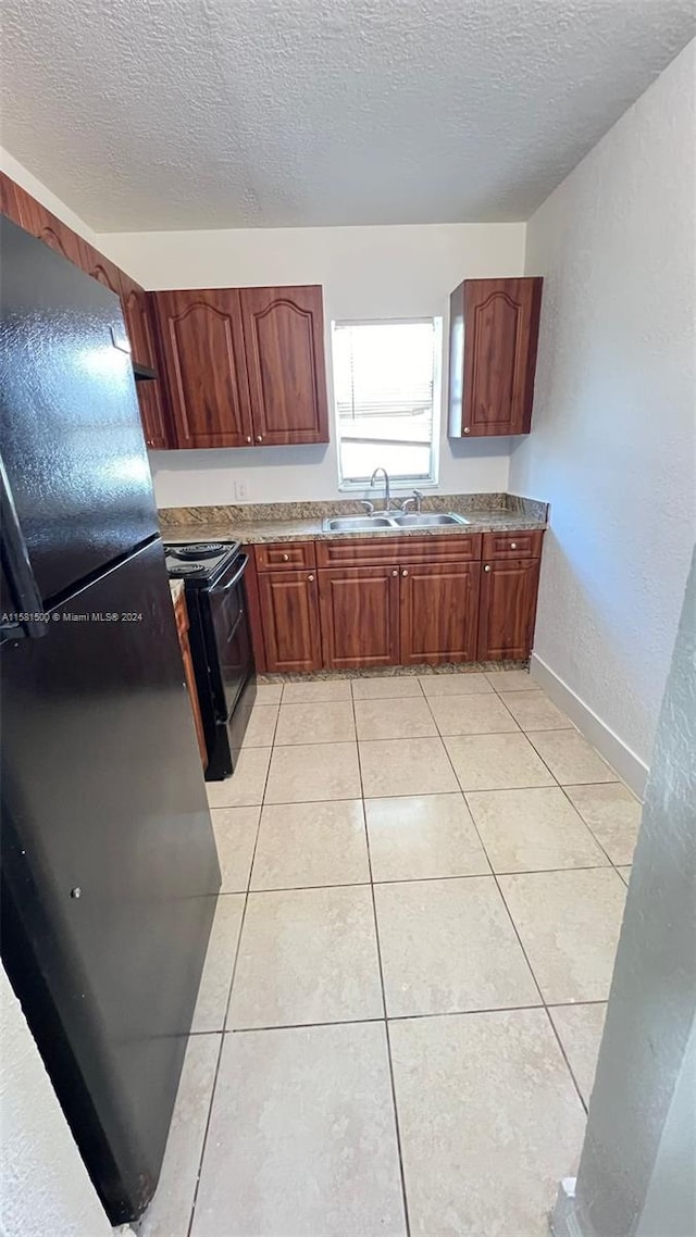 kitchen with a textured ceiling, sink, light tile floors, and black appliances