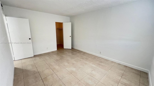 unfurnished bedroom featuring a textured ceiling, a closet, and light tile floors