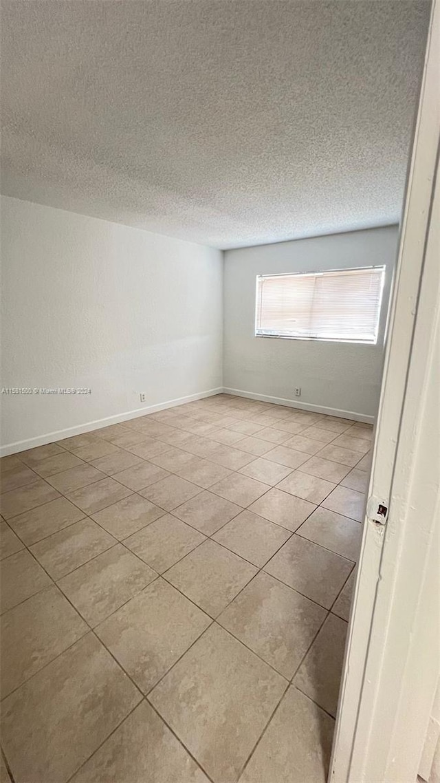 spare room with tile flooring and a textured ceiling