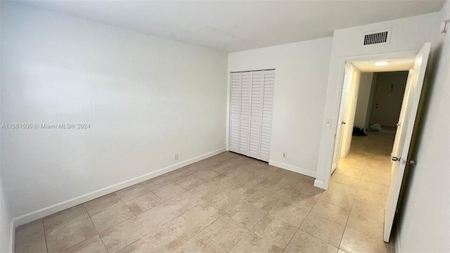 unfurnished bedroom with a closet and light tile floors