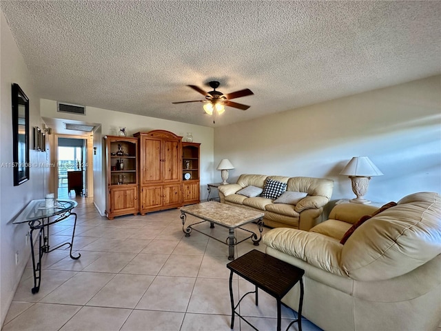 living room with light tile floors, ceiling fan, and a textured ceiling