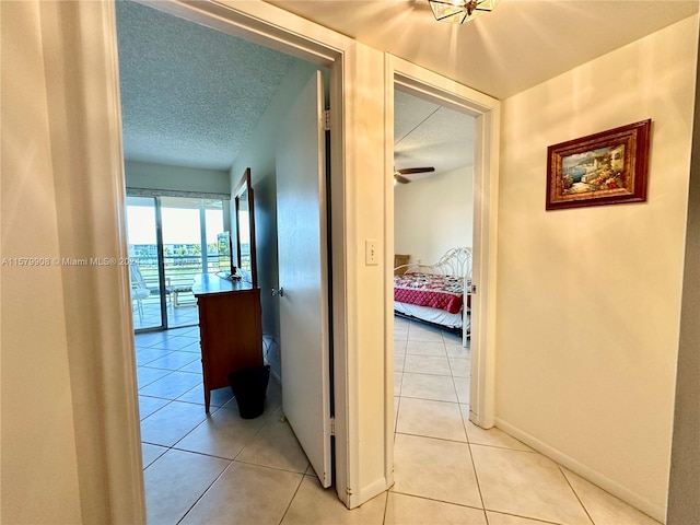 corridor with light tile floors and a textured ceiling