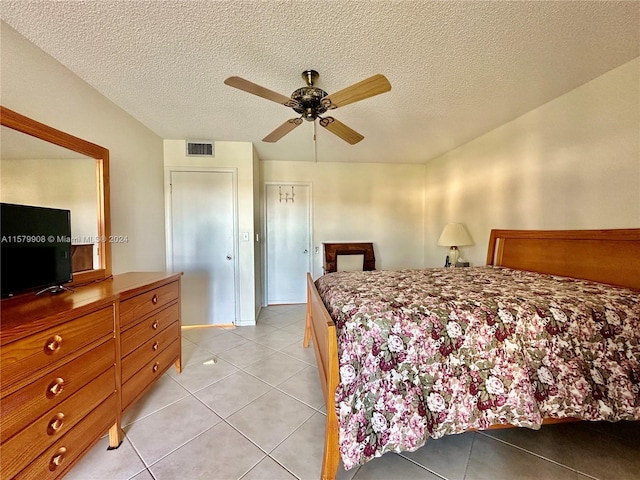 bedroom featuring ceiling fan, light tile flooring, and a textured ceiling