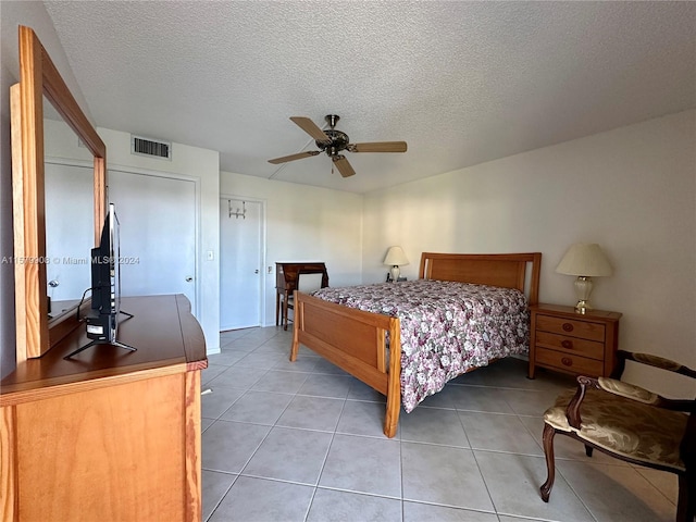 tiled bedroom with ceiling fan and a textured ceiling