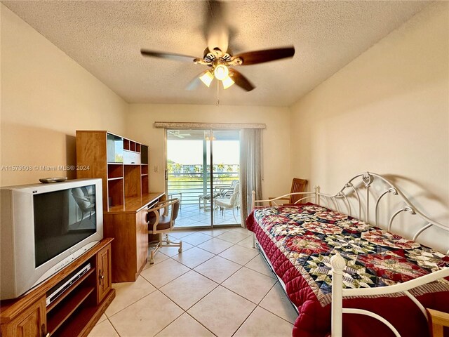 bedroom with ceiling fan, light tile flooring, access to exterior, and a textured ceiling