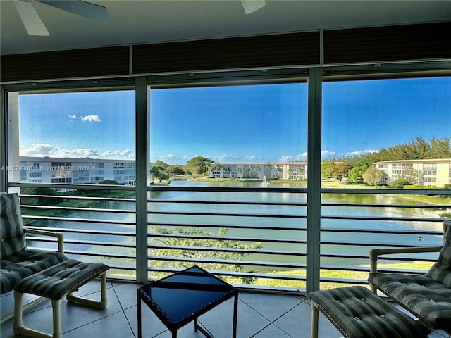 sunroom featuring ceiling fan and a water view