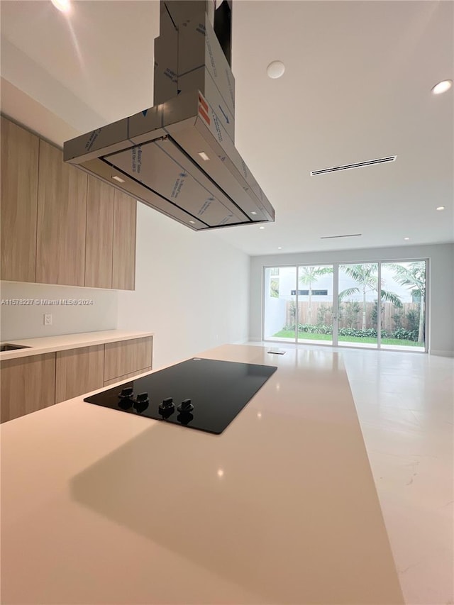 kitchen featuring black electric cooktop, light brown cabinets, and island range hood