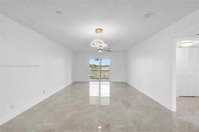 tiled empty room featuring ceiling fan and a textured ceiling