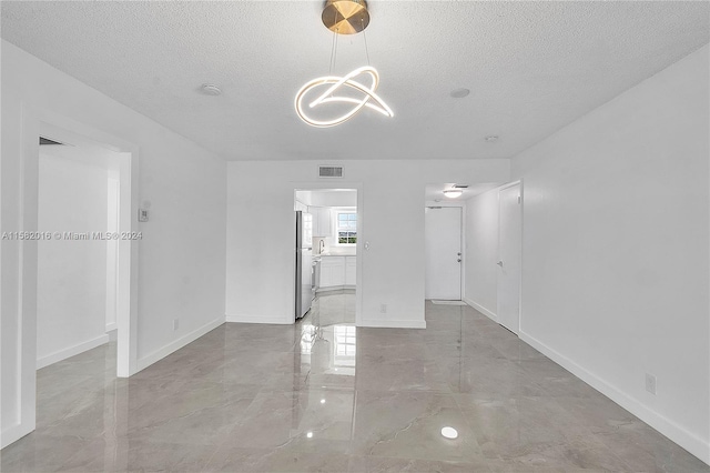 tiled empty room featuring a textured ceiling