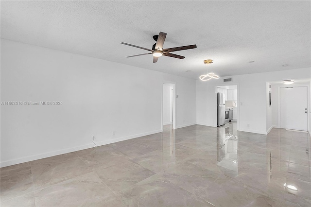 tiled empty room featuring ceiling fan and a textured ceiling