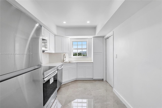 kitchen with sink, appliances with stainless steel finishes, white cabinetry, and light tile floors