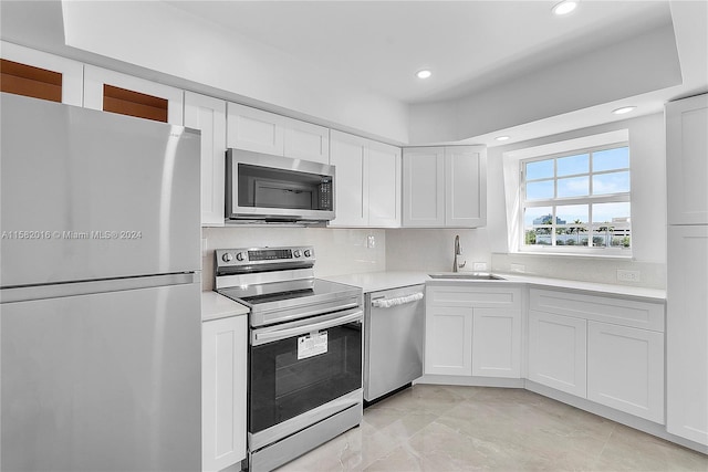 kitchen featuring stainless steel appliances, tasteful backsplash, white cabinets, sink, and light tile floors