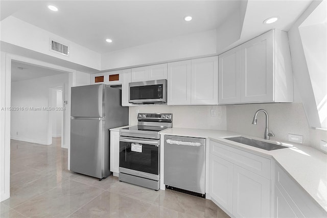 kitchen featuring appliances with stainless steel finishes, sink, light tile floors, and white cabinetry