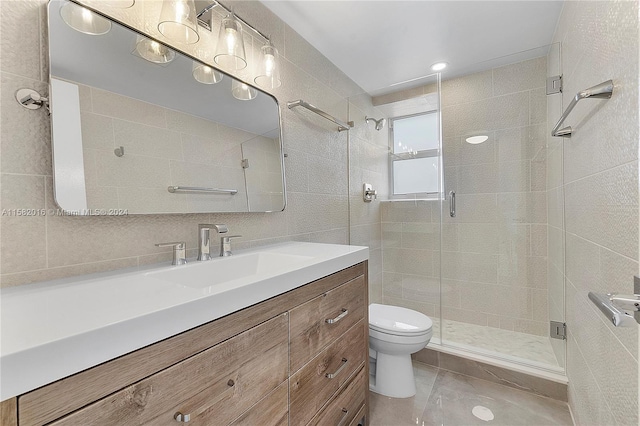 bathroom with tile walls, oversized vanity, toilet, tile flooring, and an enclosed shower