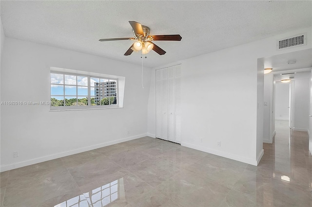 unfurnished room with a textured ceiling, ceiling fan, and light tile floors