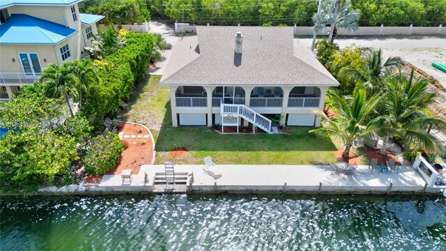 back of property featuring a water view, a yard, and a sunroom