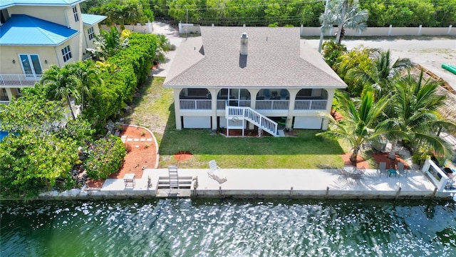 back of property featuring a water view, a yard, and a sunroom