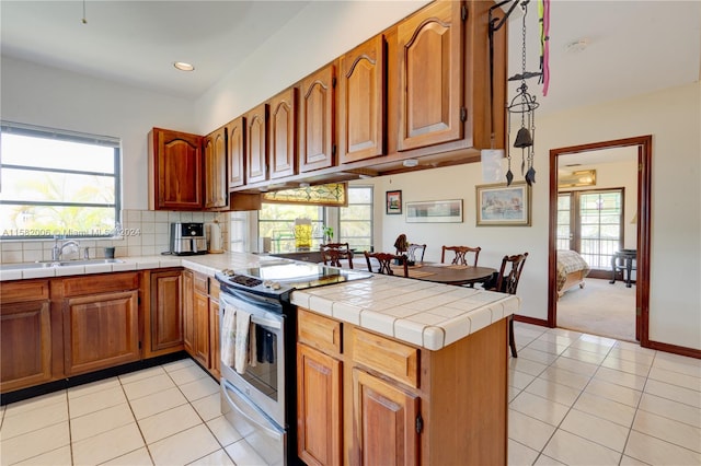 kitchen with stainless steel range with electric cooktop, a wealth of natural light, kitchen peninsula, and light colored carpet