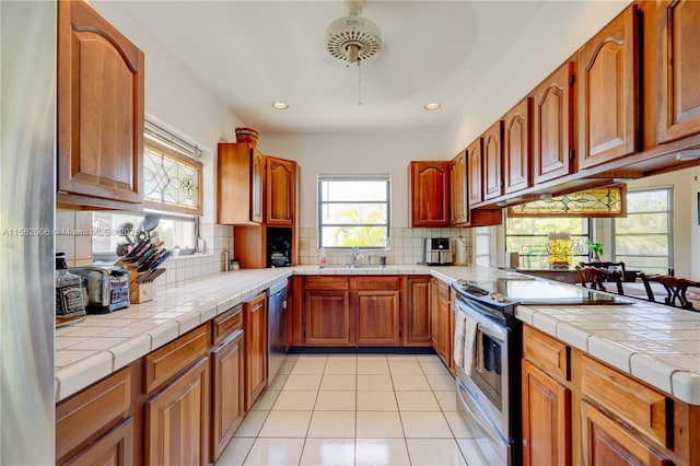 kitchen featuring tile counters, light tile patterned flooring, decorative backsplash, and stainless steel appliances