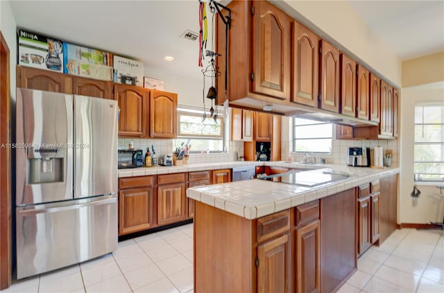 kitchen featuring stainless steel refrigerator with ice dispenser, black electric stovetop, backsplash, and tile countertops