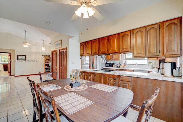 kitchen with light tile patterned flooring, vaulted ceiling, ceiling fan, and tasteful backsplash