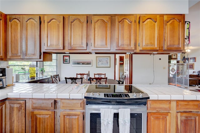 kitchen featuring kitchen peninsula, electric range, and tile countertops