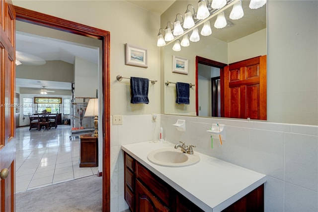 bathroom featuring tile walls, tile patterned flooring, lofted ceiling, ceiling fan, and vanity