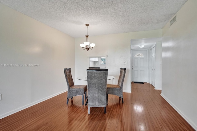 dining area featuring hardwood / wood-style flooring, a textured ceiling, and a chandelier