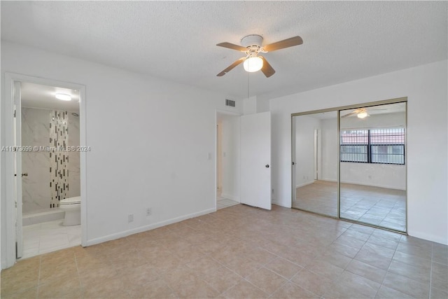 unfurnished bedroom with a closet, light tile flooring, connected bathroom, ceiling fan, and a textured ceiling