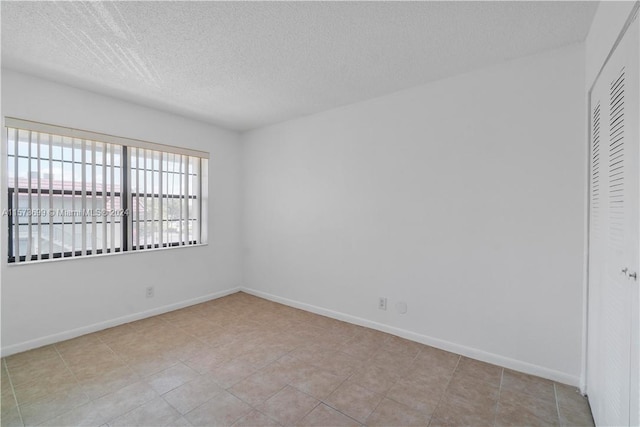 tiled spare room featuring a textured ceiling