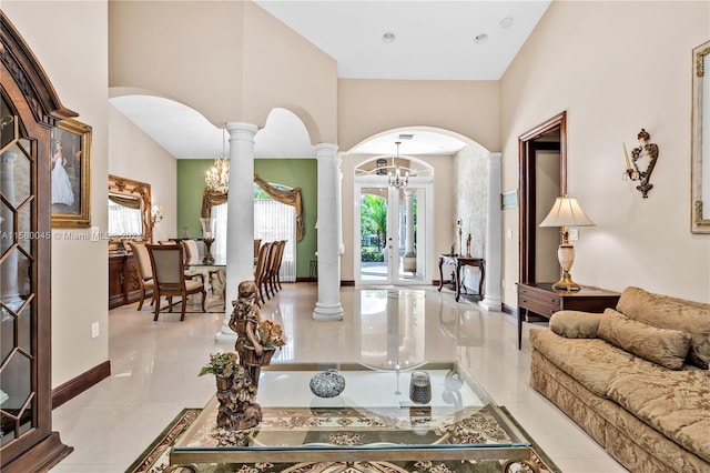 tiled living room with an inviting chandelier, french doors, decorative columns, and a high ceiling