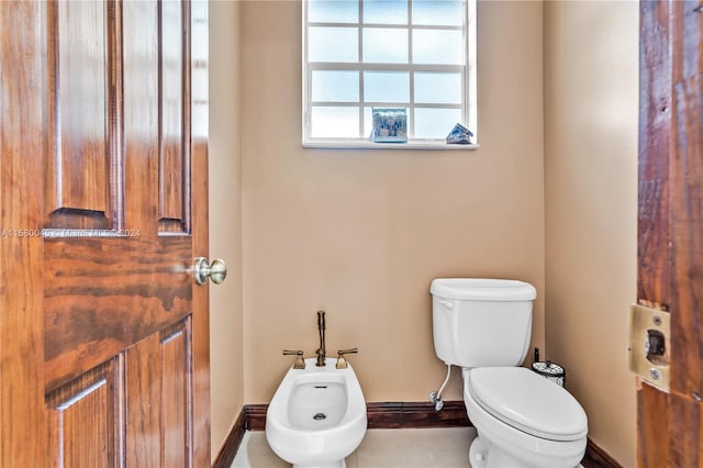 bathroom featuring tile patterned flooring, toilet, and a bidet