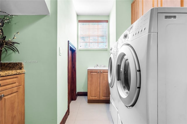 washroom with light tile patterned flooring, cabinets, and washer and dryer