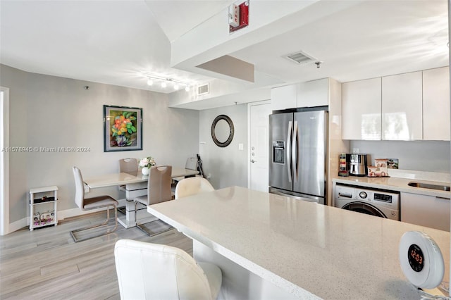 kitchen with light hardwood / wood-style floors, white cabinetry, rail lighting, washer / clothes dryer, and stainless steel refrigerator with ice dispenser