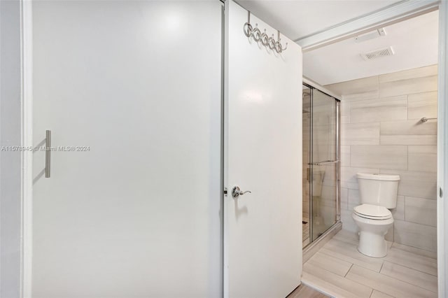 bathroom with walk in shower, toilet, tile flooring, and tile walls