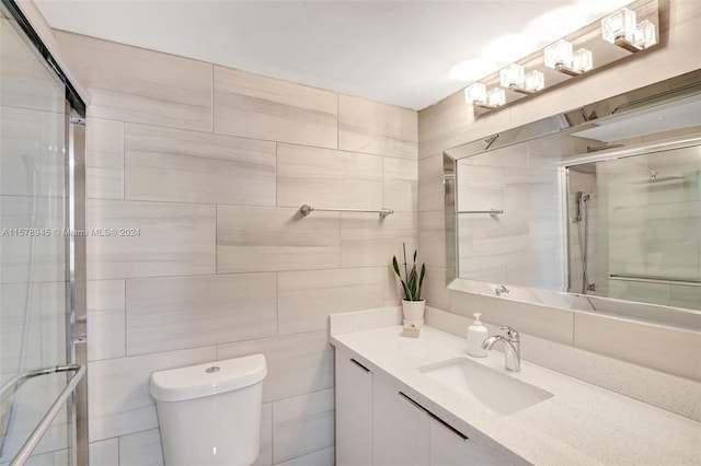 bathroom with a shower with shower door, toilet, tile walls, and large vanity