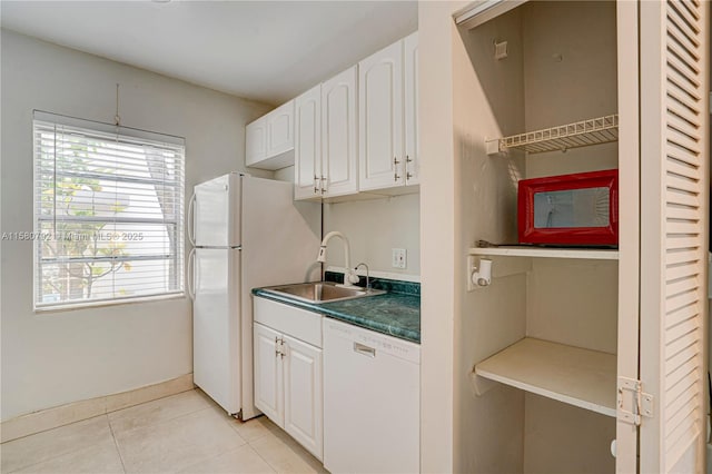 kitchen with sink, white appliances, white cabinetry, a healthy amount of sunlight, and light tile patterned floors