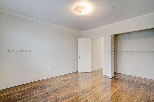 unfurnished bedroom featuring a closet, a textured ceiling, ornamental molding, and wood-type flooring