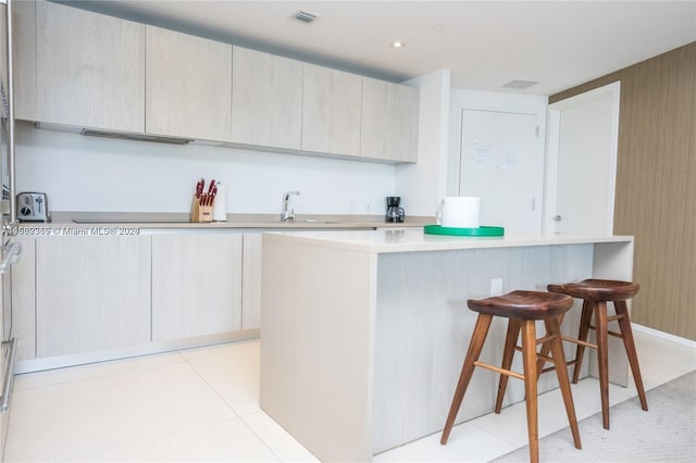 kitchen featuring a kitchen breakfast bar, sink, a center island, and light tile floors