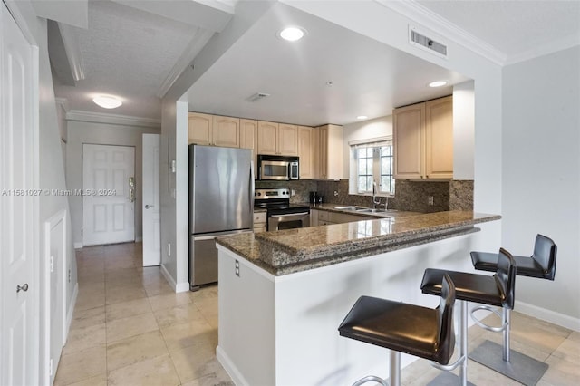 kitchen with light brown cabinetry, kitchen peninsula, stainless steel appliances, sink, and tasteful backsplash